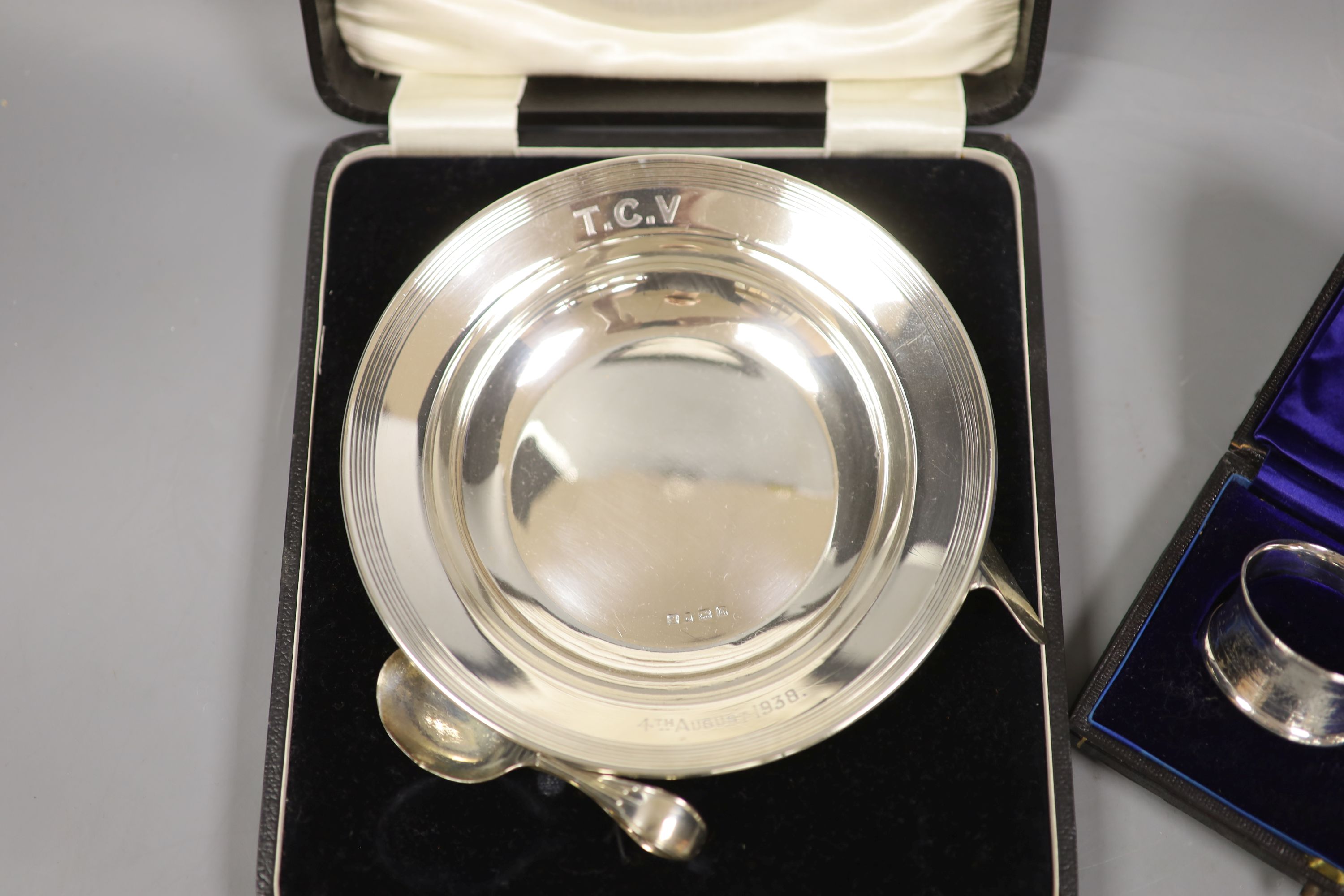 A cased christening dish with associated pusher and spoon, together with a cased pair of silver napkin rings.